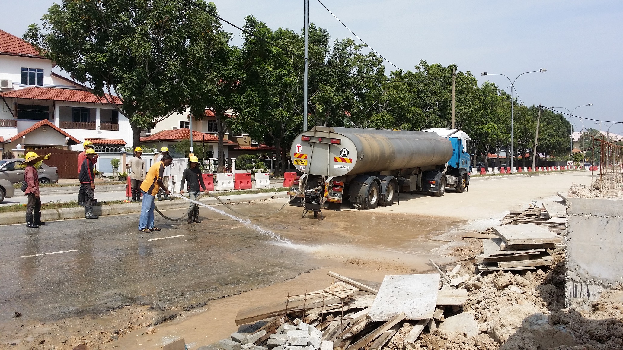 Asian construction crew in safety helmets operating beside a Terasek water tanker